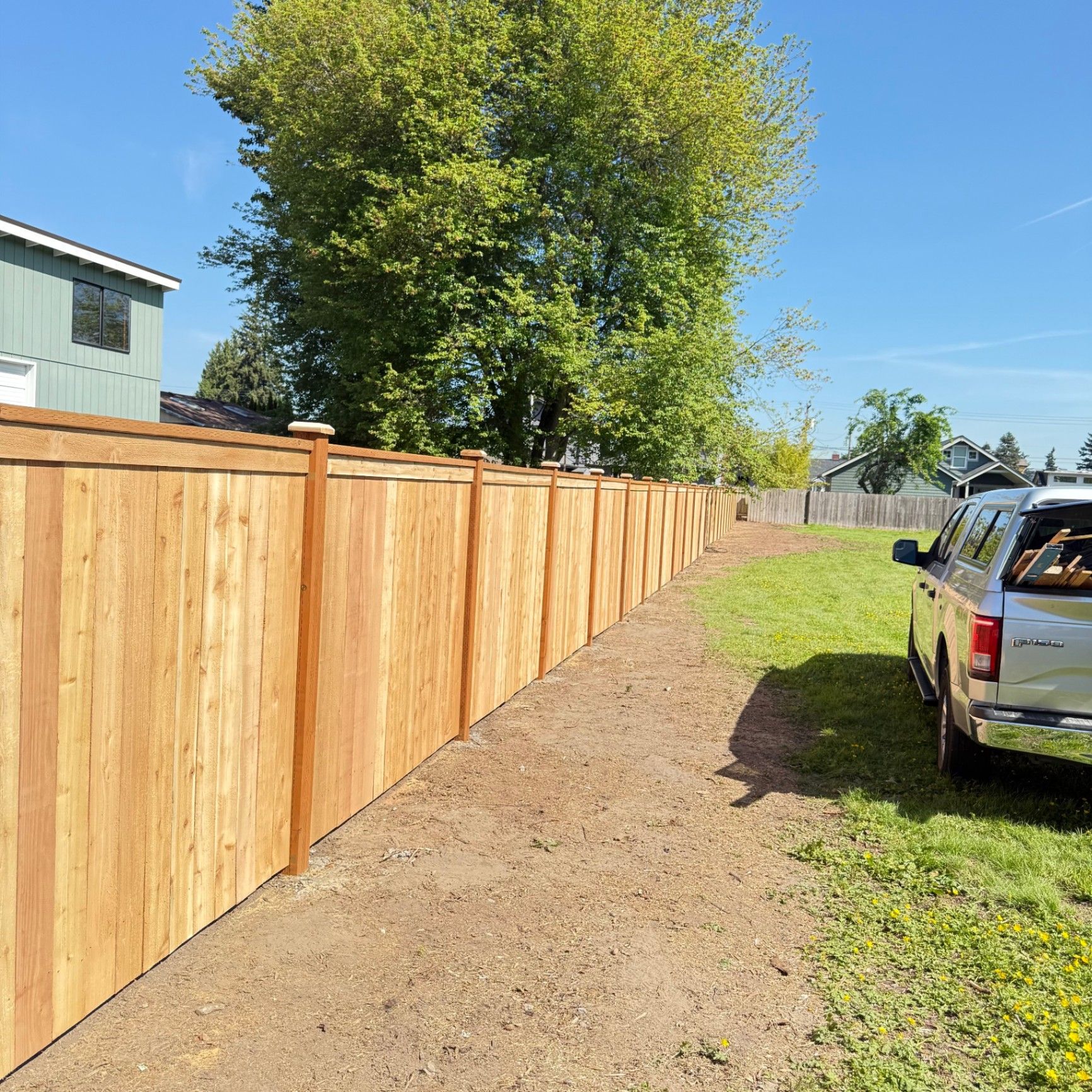 Long cedar fence with evenly spaced posts and fresh landscaping edge
