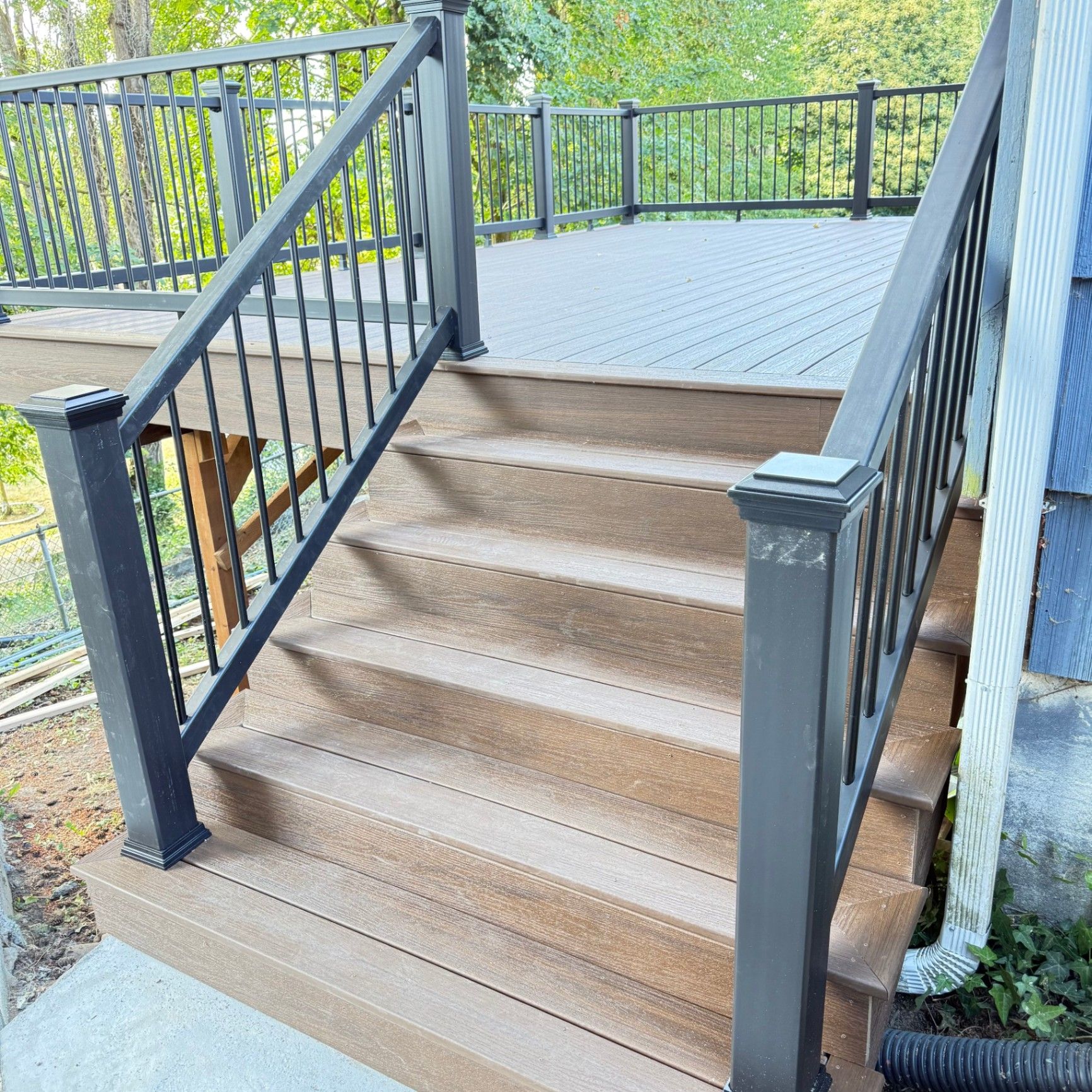 Bright white-railed deck with wide boards opening toward a front yard