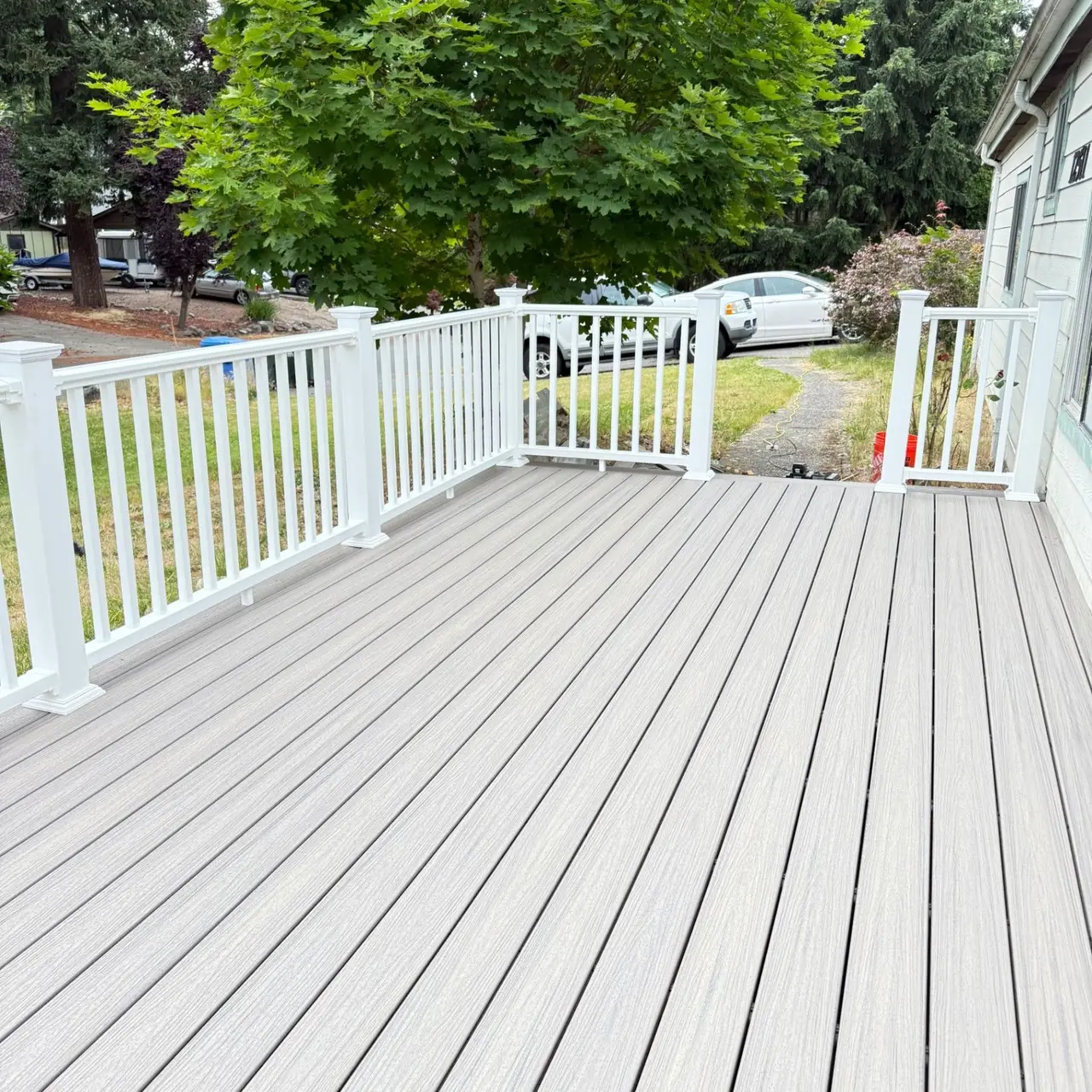 Light gray deck with white railings beside a residential yard